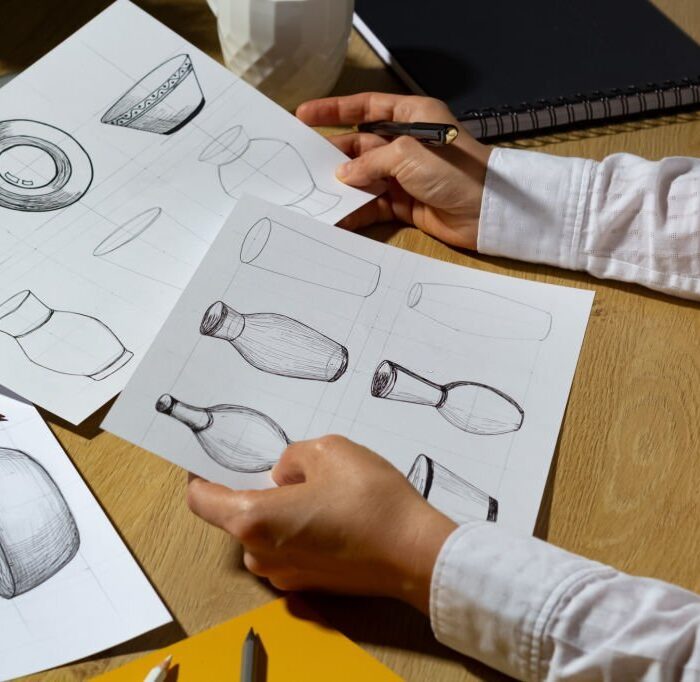 The designer draws sketches of dishes on paper. The artist creates kitchen utensils for production.