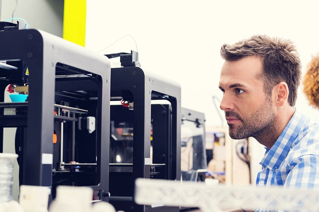 Man working in a 3d printer office, watching at 3d printout.